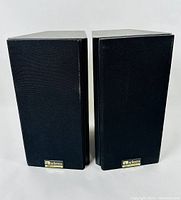 Pair of black Axiom bookshelf speakers with fabric grills installed, front view.