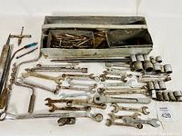View of all included tools laid out from the metal compartmentalized tool tray, showing the variety of wrenches and sockets including T-handles and ratchets.
