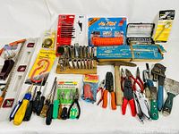 A wide view of all the hand tools and accessories in the lot, many still in packaging, arranged neatly on a white background.