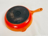 Bottom view showing orange enamel exterior and black cast iron base with markings 'Made in France' and size '23'.