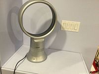 Front view of Air Plex bladeless fan showing circular ring and control buttons on base with power cord attached.