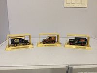 Four vintage collectible truck models mounted on cream display stands, lined up in a row.