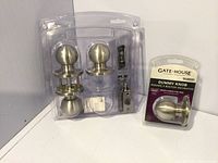 Two packs of stainless steel finish round door knobs: one 2-pack keyed entry set with latch and strike plate, and one single dummy knob in package