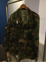 Front view of camouflage blouse showing button-up front, pockets, and SeaBees logo.