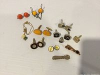 Full lot overview showing earrings, cufflinks, necklace and tie clips on white surface.