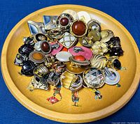 Photo of about 25 vintage costume earrings on a wooden plate, various styles and colors, some marked Vendome.