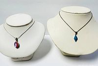 Full view showing both necklaces on display busts with distinct pendants.