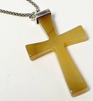 Close-up of amber-colored semi-precious stone cross pendant with silver bail marked 925 attached to silver chain