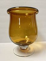 Front and side view showing amber glass hurricane style bowl with clear pedestal base on white background