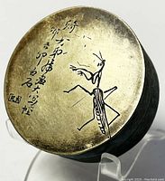 Top view of trinket box lid showing etched praying mantis and Chinese script with signature