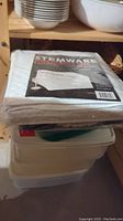 Photo of stacked clear white Rubbermaid storage containers with lids under shelf.