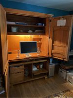 Front view of open Ethan Allen armoire desk cabinet with work surface, shelves, computer monitor, drawers below, and built-in lighting