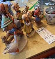 Six German Goebel figurines including children in traditional attire and two Royal Worcester egg coddlers on a table