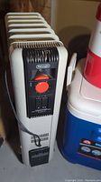 View of the entire heater showing its casters, off-white body, power cord, and the black control panel with red dial.