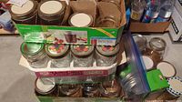 Photo showing stacked and boxed canning jars including new Ball jars and assorted lids