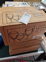 Closed cardboard box labeled 'Classic Wine Glasses' and '10 oz Handy Mug Snowman w/broom mug'