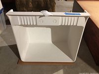 Front view of white utility sink showing ribbed reinforcement design and two knock-out holes for accessories.
