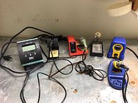 Overview of three soldering stations on bench: Weller WD1 (left), WLC100 (center), blue station (right)