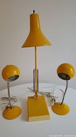 Three lamps grouped on table: one tall adjustable lamp and two small spherical-head lamps