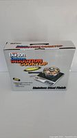 Box of Burton Deluxe Induction Cooktop showing stainless steel finish and cooked food on the cooktop in image.