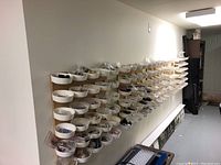 Wall-mounted rows of white plastic sorting trays filled with various loose hardware items packed in plastic bags on wooden backboards.