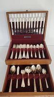 Full view of wooden box open displaying the silver plated cutlery organized inside.