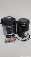 Crock-Pot multi-cooker and T-fal air fryer shown side by side, including recipe book under Crock-Pot