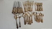 Overall layout of Wallace Meadow Rose sterling silver flatware pieces on white background.