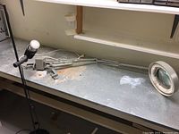 Overview of the lot showing the floor lamp standing upright and the Luxo magnifier lamp head lying on the workbench.