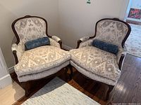 Two upholstered armchairs side by side showing overall condition, upholstery pattern and frame detail