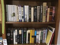 Bookshelf with two shelves filled with novels, biographies, and history books, showing spines clearly to identify some titles and authors.