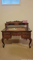 Full front view of the solid wood carved desk with raised shelf and items on top