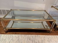 Full front view of coffee table showing brass-tone frame, glass top and mirrored bottom shelf
