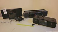 Panasonic SC-HC20 stereo system, vintage Toshiba boom box, and Panasonic alarm clock radio arrayed on a flat surface.