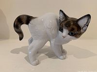 Front and side view of the cat figurine, showing glossy porcelain surface and color details