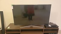 Front view of Samsung 55-inch LED TV on silver V-shaped stand on media console.