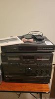 Stack of Technics stereo system components: CD player, cassette deck, receiver, synthesizer with remote and cables on top