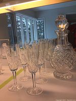 Front view of Waterford crystal decanter with stopper and six matching flutes arranged behind.