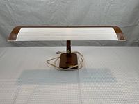 Front view of vintage banker’s lamp showing ribbed white glass shade with wooden ends, wooden base with switch, and white cord.