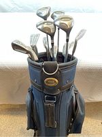 Front view of blue Power Bilt golf bag filled with various golf clubs, showing club heads and top of bag.