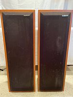 Front view of both Studio Lab floor-standing stereo speakers showing black fabric grilles and wood veneer sides.