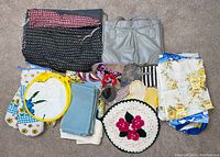 Full lot laid out showing various bags, purse, kitchen linens, aprons, and trivets.