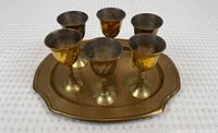 Image showing the brass tray with six brass cups arranged on it, highlighting tarnish and patina on the metal surfaces.