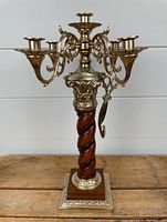 Front view of vintage candelabrum showing wooden twisted column and brass candle holders with snuffer attached