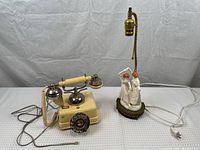 Vintage rotary dial phone and figurine lamp side by side on a table