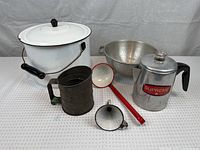 Overview of all vintage metal kitchen tools including stock pot, metal ladle, funnel, colander, coffee pot, and sifter