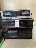 Front view of three stacked audio components: a silver Realistic SCT-72 double cassette deck on top, a black Optimus SCT-49 double cassette deck in the middle, and a black Pioneer PD-F407 CD changer on the bottom.