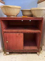 Small wooden cupboard with sliding door and shelf, worn surface, on caster wheels