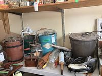 Shelf display of two hand-crank ice cream makers, juicer, meat grinder, mixer, rolling pins and butter press