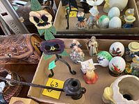 Overview of assorted decorative items including hand tooled leather purse, carved pipe, metal pansy flower decor, Easter planter with eggs and bird figures, assorted figurines, and owl figurines.